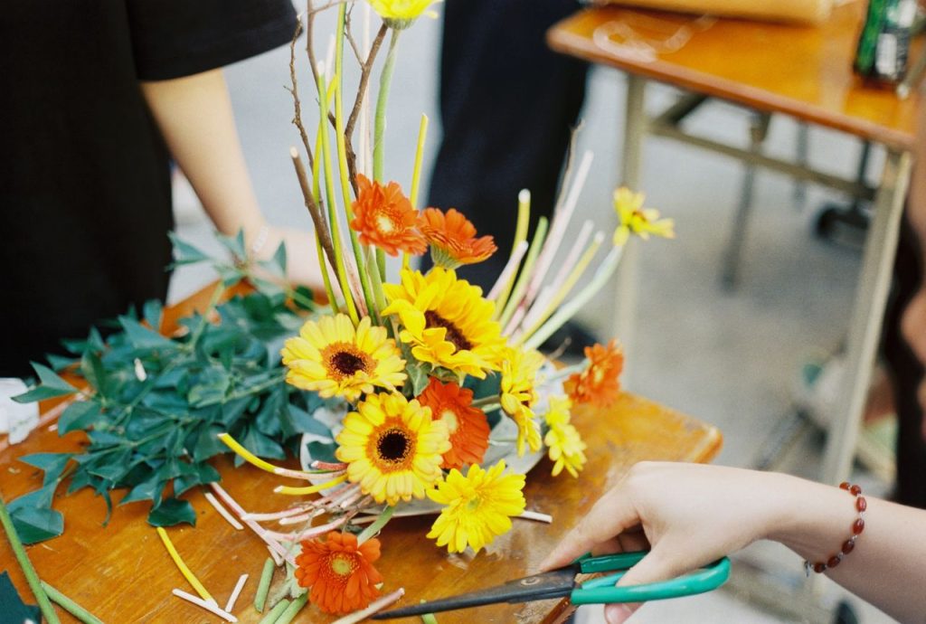 Hands arranging colorful flowers with care and precision, creating a vibrant display.